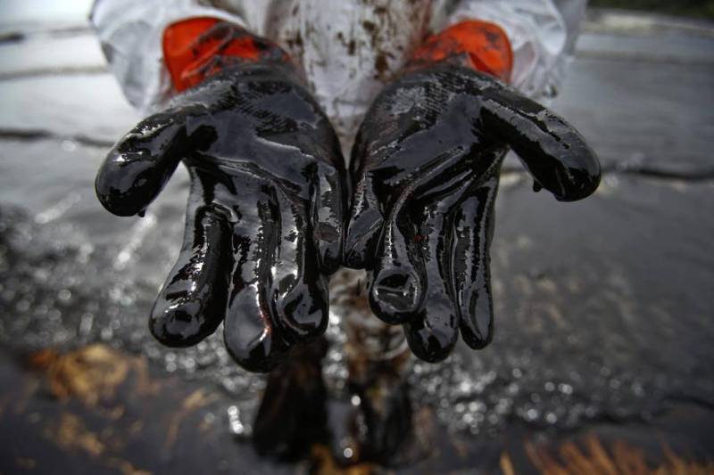 A Thai soldiers shows his glove covered with oil slick during a clean-up operation at Ao Prao Beach on Koh Samet